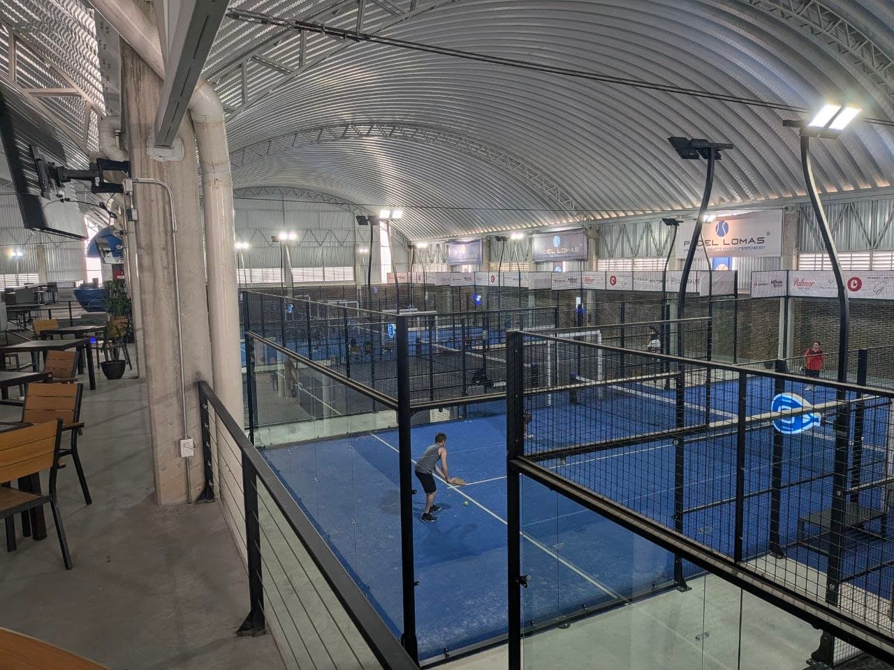 Jugador entrenando su técnica en una cancha azul de Padel Lomas